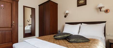 Habitación de hotel con una cama grande, un armario, un espejo y dos lámparas fijadas a la pared.