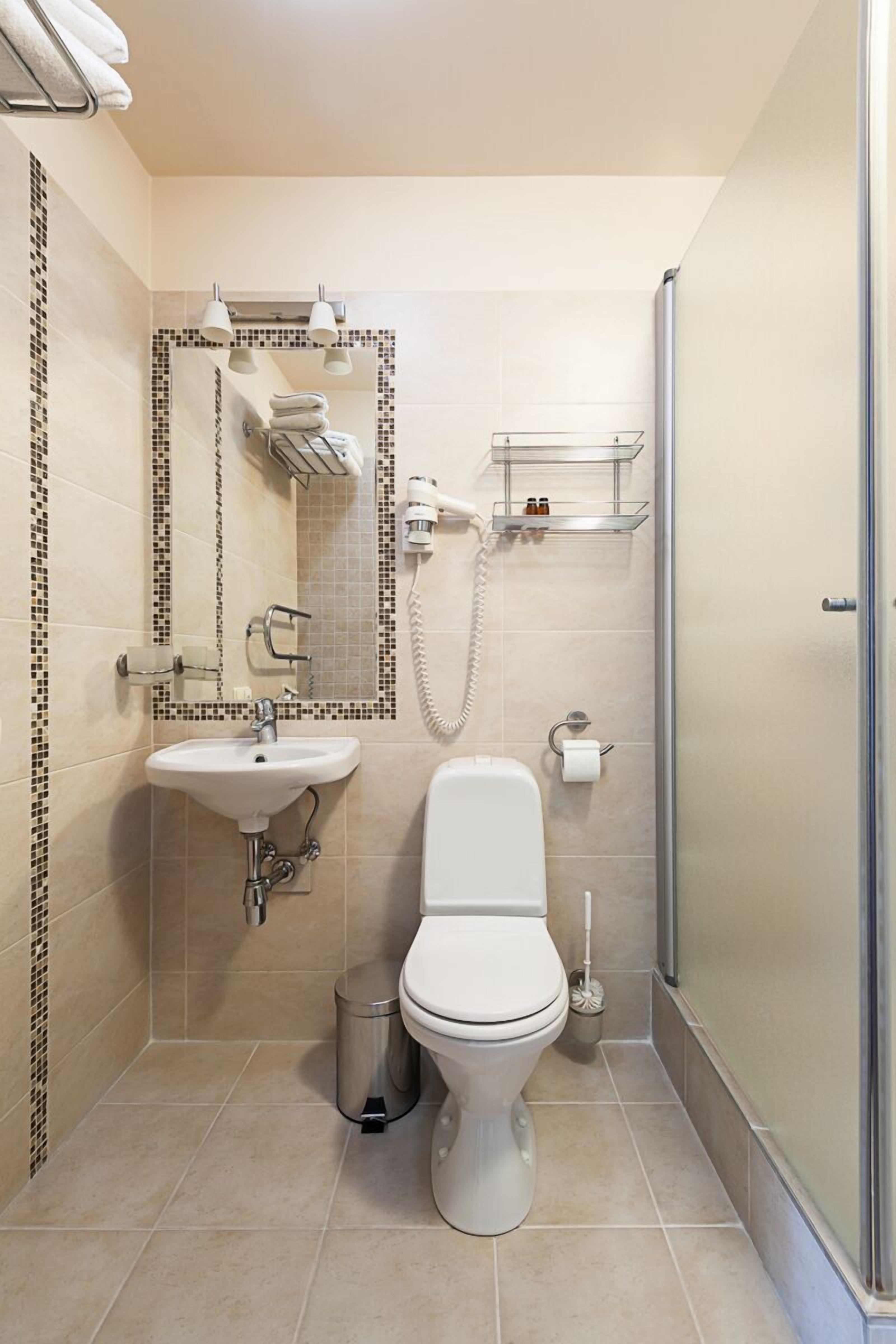 A compact bathroom with a toilet, sink, and shower area.