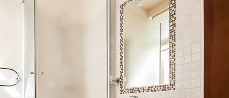 Une salle de bain moderne avec une douche à parois de verre, un lavabo blanc avec un miroir au-dessus et des toilettes.