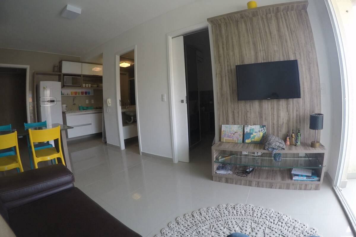 Ein modernes Wohnzimmer mit Fernseher, Glastisch und einer Couch.