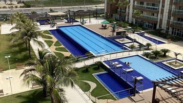 Hotel com várias piscinas, vista para a praia e área de estacionamento.