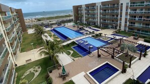 A hotel with multiple swimming pools, a beach view, and a well-maintained garden area.
