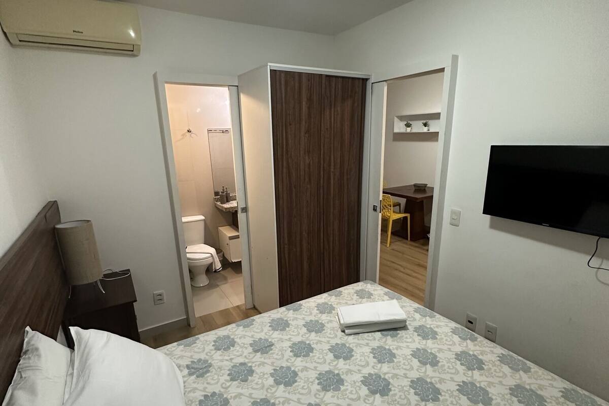 Ein Hotelzimmer mit Bett, Fernseher, Kleiderschrank und angrenzendem Badezimmer.