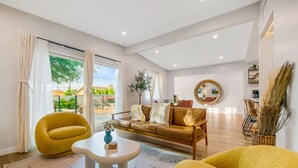A modern living room with a sofa, armchairs, a coffee table, and a large window with curtains.