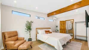 A bedroom with a bed, a chair, a potted plant, and a TV.