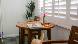 A wooden table with a bottle, glasses, and a magazine.