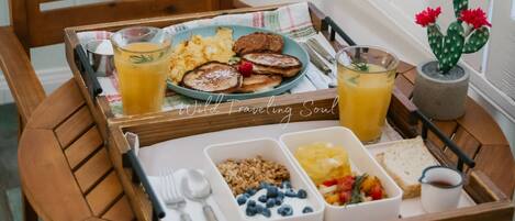 A wooden dining table with breakfast items including pancakes, eggs, and orange juice.
