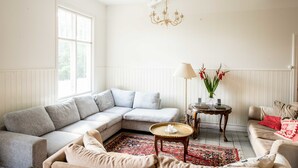 Un salon avec un canapé d’angle, une table basse ronde et un tapis à motifs.