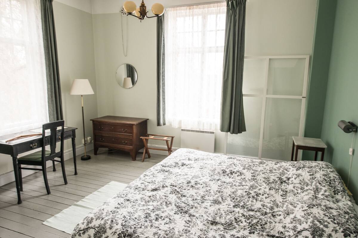 Une chambre à coucher comprenant un lit, un bureau, une chaise, une commode et un miroir.