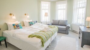 Une chambre à coucher avec un grand lit, un canapé gris et deux lampes de chevet.