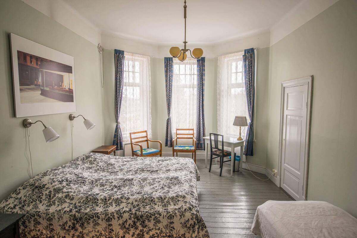 Une chambre à coucher avec un grand lit, deux chaises, un bureau et une porte.