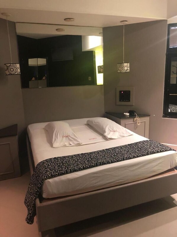 A modern hotel room with a large bed, a bedside table, a mirror, and a control panel. - Origen Hotel (Motel) (Buenos Aires)