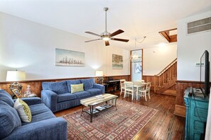 A living room with a blue sofa, a coffee table, and a wooden staircase. - Gallery Stays - Pop Collection (Savannah)