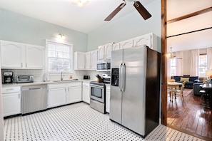 A modern kitchen with white cabinets, stainless steel appliances, and a patterned floor. - Gallery Stays - Pop Collection (Savannah)