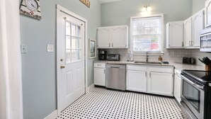 Une cuisine avec des meubles blancs, un four à micro-ondes, un lave-vaisselle et une cuisinière.