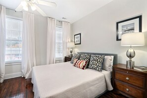 A bedroom with a large bed, a nightstand, a lamp, and a framed picture on the wall. - Gallery Stays - Pop Collection (Savannah)