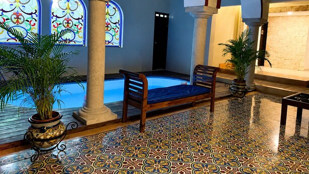 A pool area with a bench, columns, and a tiled floor. - Hotel Catedral Valladolid (Valladolid)