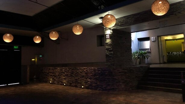 A lobby with stone walls, a staircase, and hanging spherical light fixtures. - Uman Hotel (Motel) (Buenos Aires)
