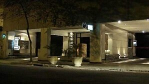 A hotel entrance at night with a well-lit facade, potted plants, and a visible sign. - Uman Hotel (Motel) (Buenos Aires)