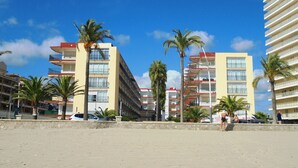 A beachfront hotel with multiple floors, balconies, and palm trees. - Les Doyes Bl 4 pta 145 (Peñiscola)