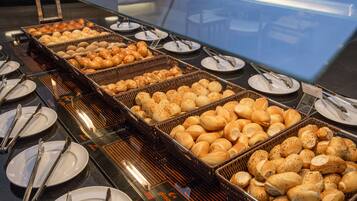 Um buffet com diversos pães e doces dispostos em cestas de vime.