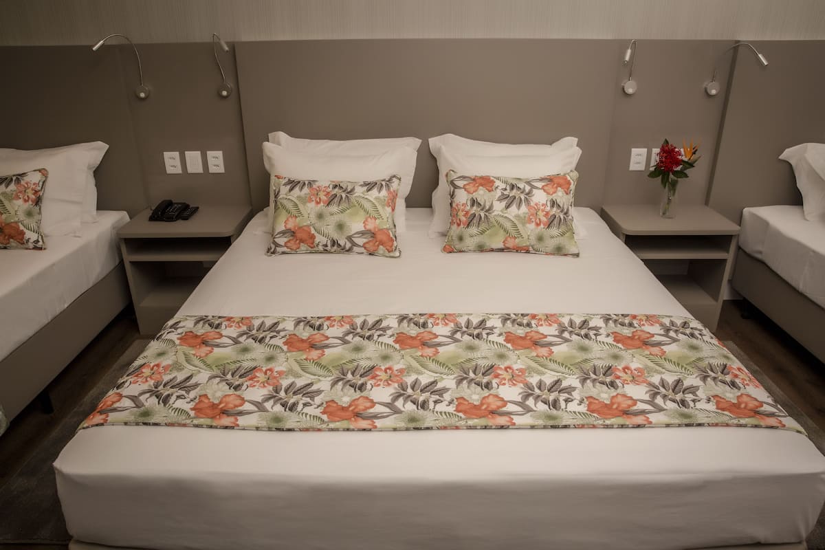 A hotel room with a large bed, two bedside tables, and a nightstand with a phone.