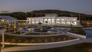Un edificio moderno con un patio central, rodeado de zonas ajardinadas y palmeras.