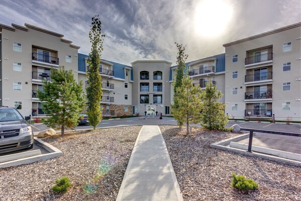 A modern apartment complex with a central courtyard, a parking area, and a clear sky. - Eaglemont Manor (Beaumont)
