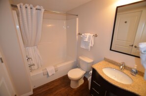 Une salle de bain équipée d’une baignoire, de toilettes, d’un lavabo et d’un miroir.