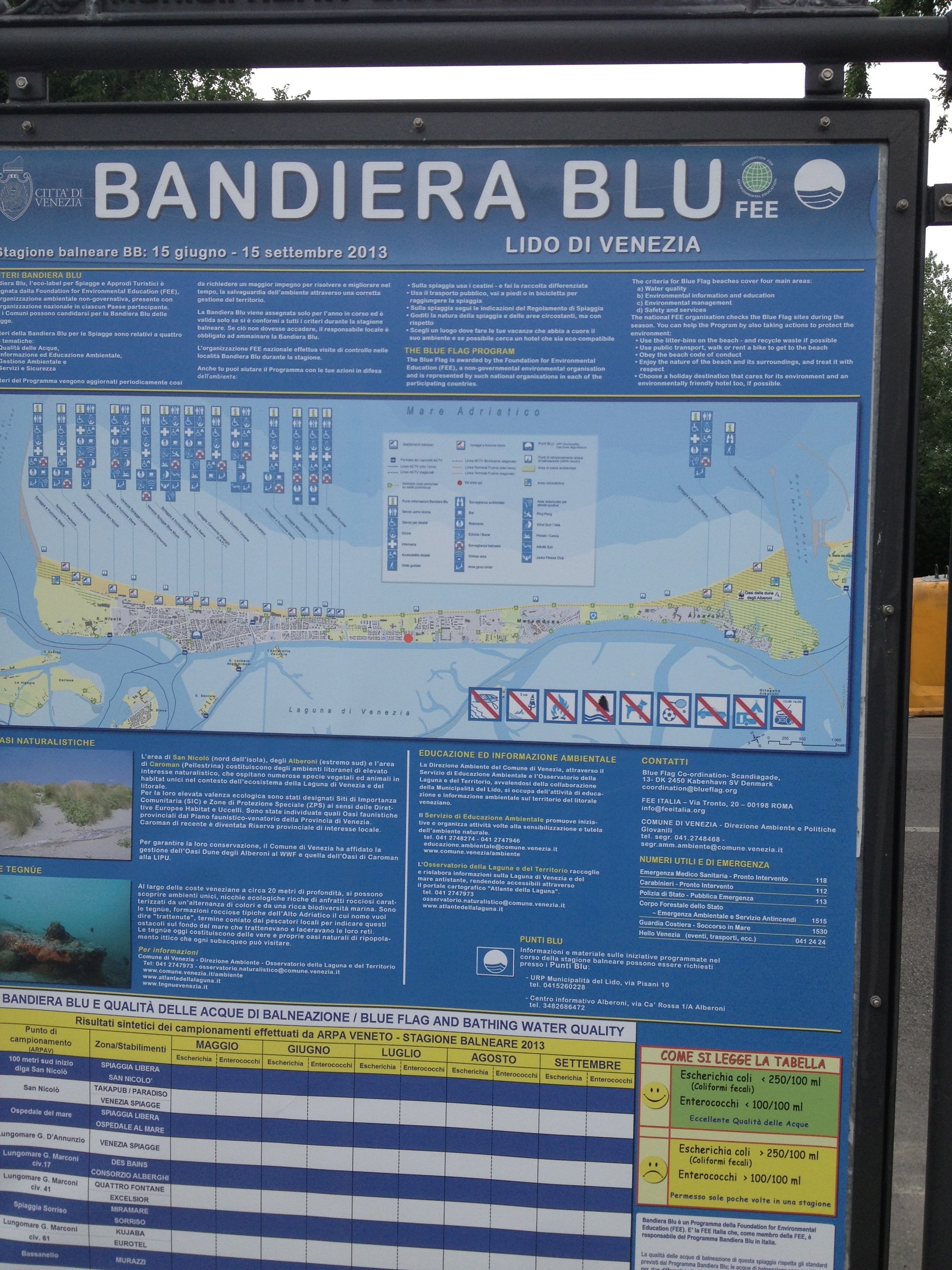 Un detallado cartel informativo sobre la zona de playa Bandiera Blu en Venecia, con mapas, datos sobre la calidad del agua y directrices ambientales.