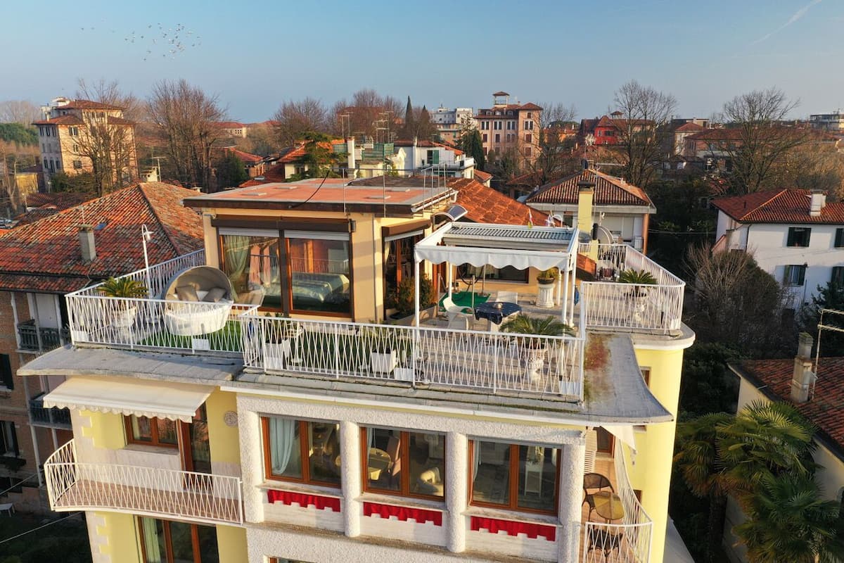 A multi-story building with balconies, large windows, and a satellite dish.