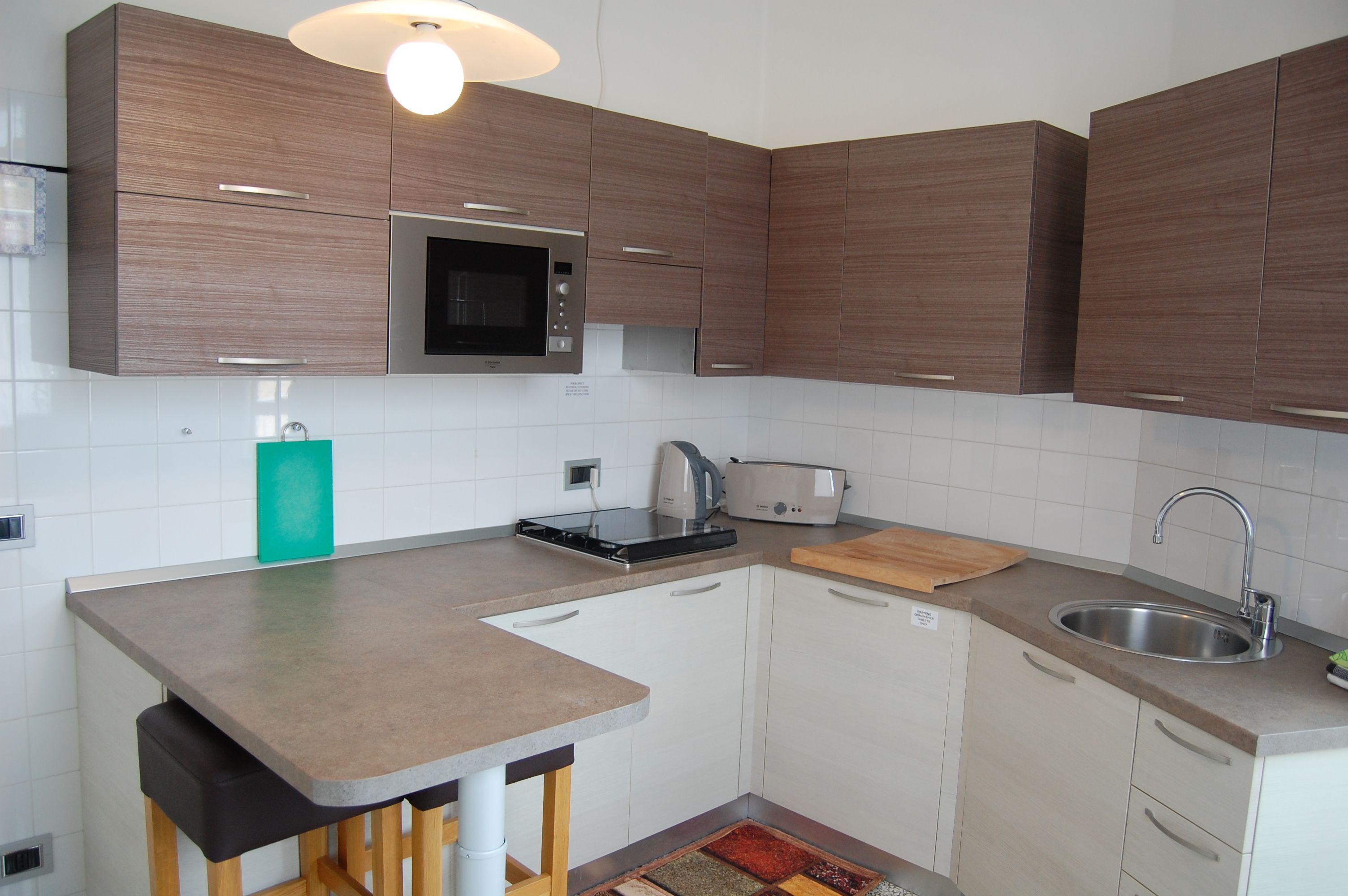 A modern kitchen with wooden cabinets, a built-in microwave, a toaster, and a sink.