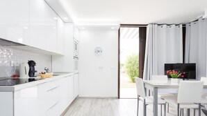 Eine moderne Küche mit weißen Schränken, einer schwarzen Arbeitsplatte und einem Essbereich mit Tisch und Stühlen.