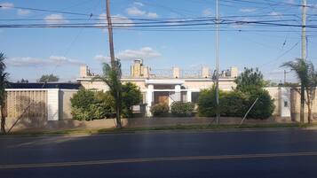 Un hotel con fachada simétrica, varias chimeneas y una entrada con puerta de hierro forjado.