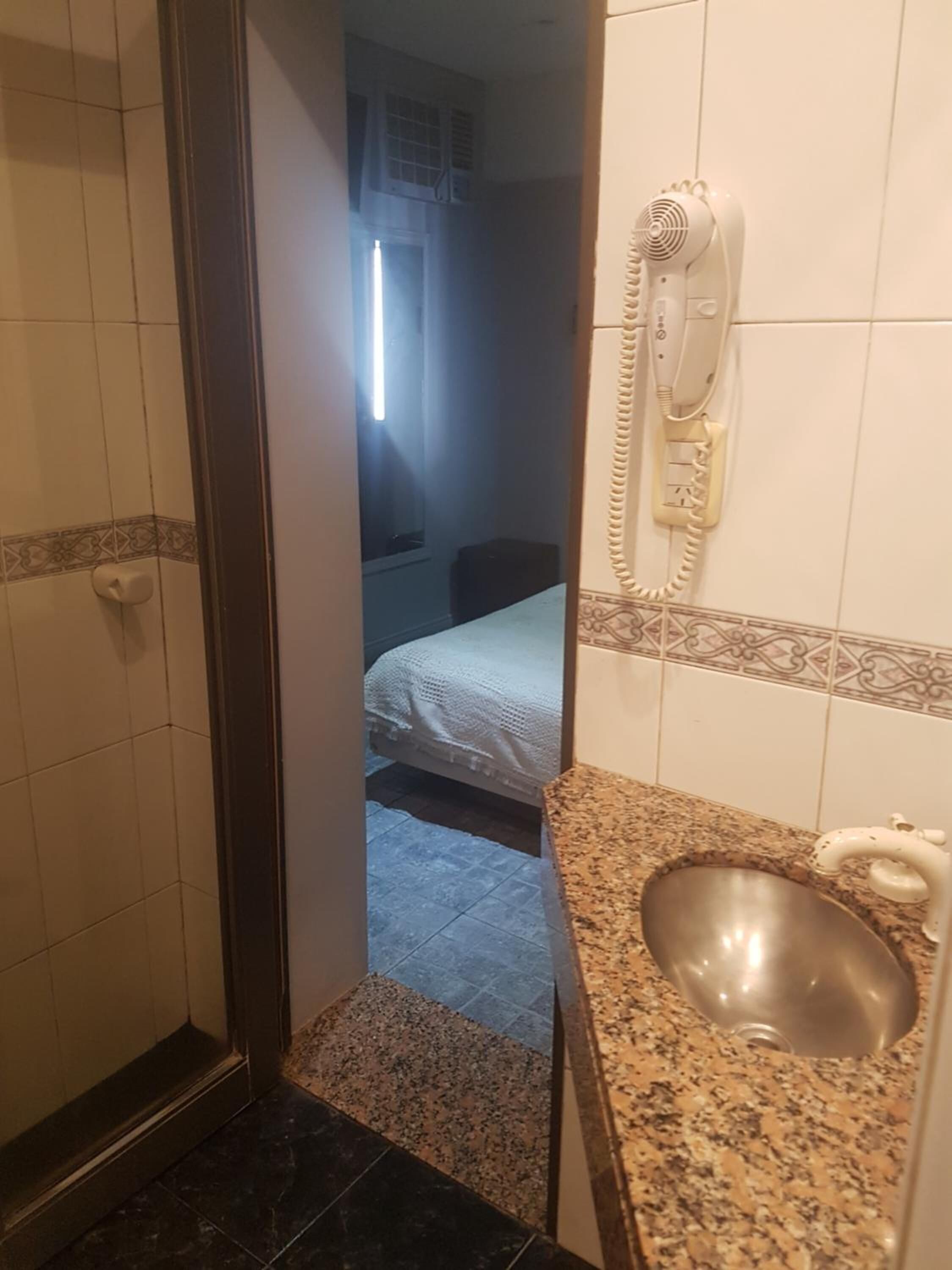 A bathroom with a sink, a mirror, and a telephone.