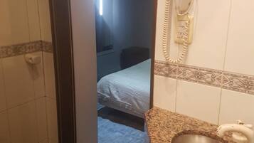 A bathroom with a sink, a mirror, and a telephone.
