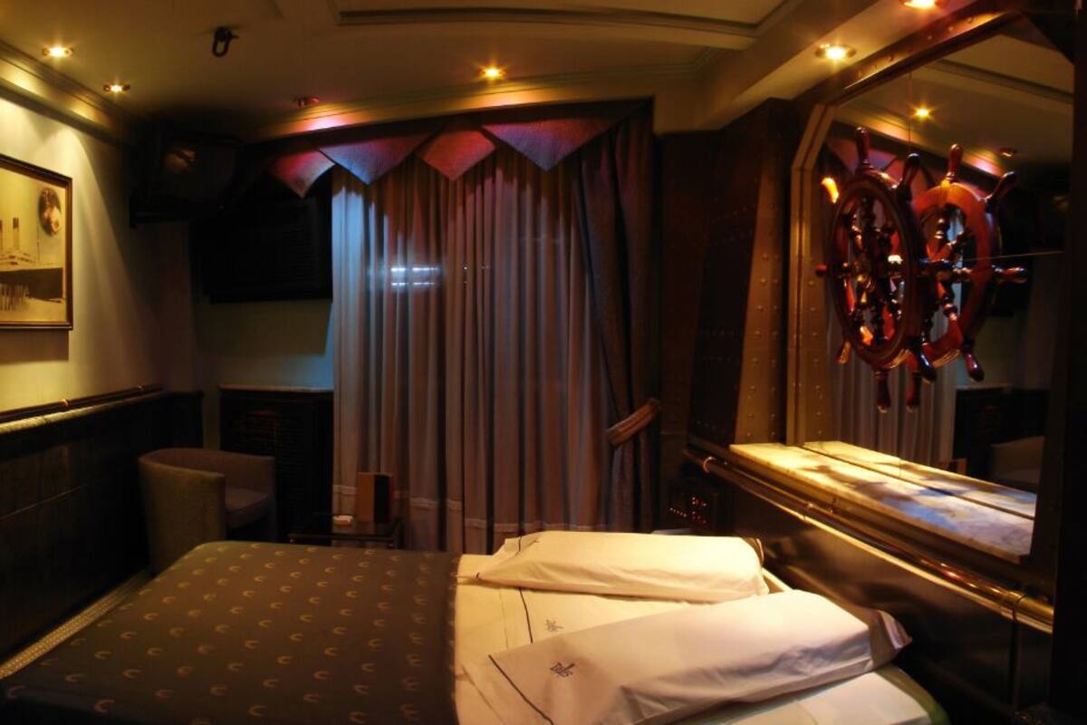 A hotel room with a bed, a desk, and a large mirror.