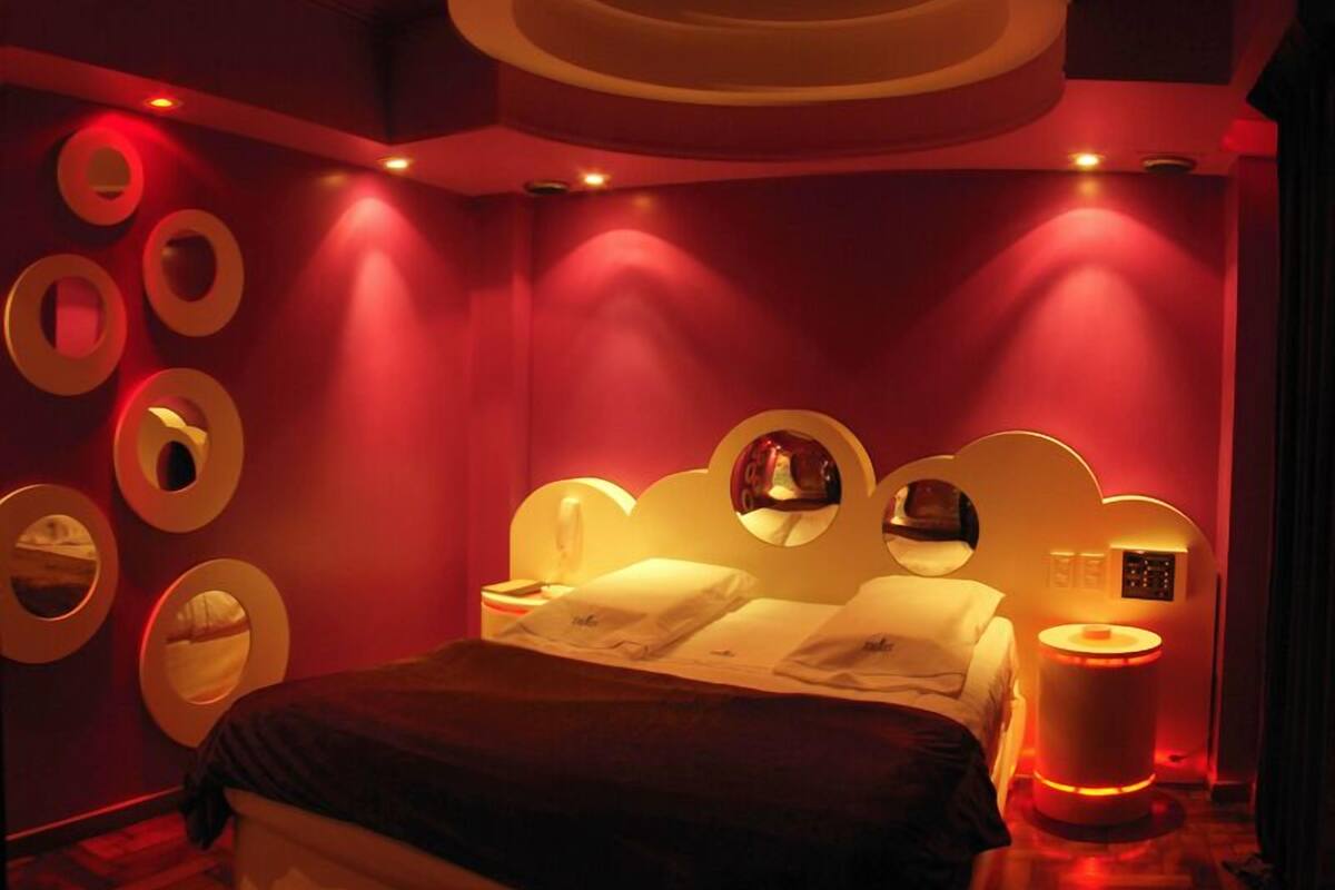 A modern bedroom with a bed, circular wall mirrors, and ambient lighting.