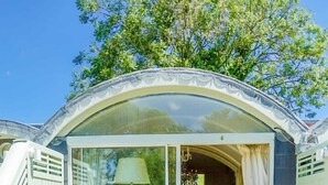 A covered patio with a table and chairs, a glass door leading inside, and a view of the garden. - Cedar House Boutique B&B (Christchurch)