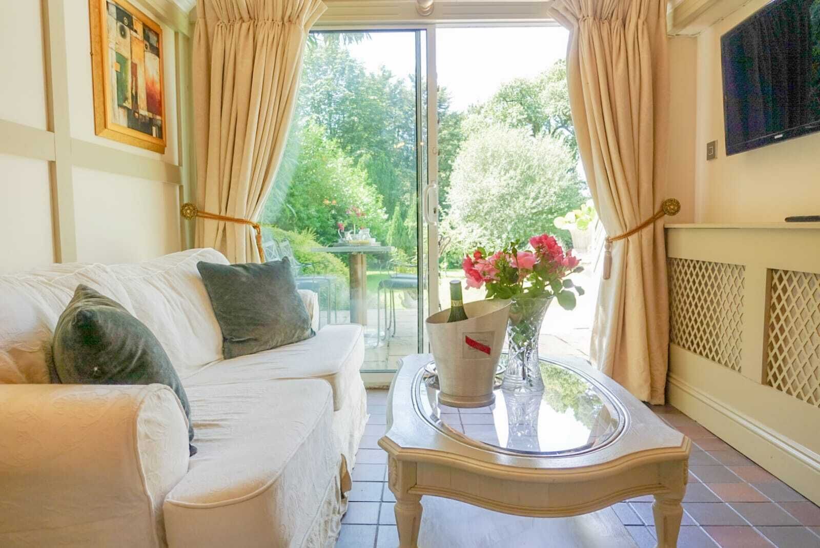 A living room with a white sofa, a glass coffee table, and a vase with flowers.