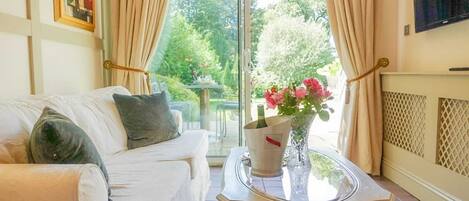 A living room with a white sofa, a glass coffee table, and a vase with flowers.