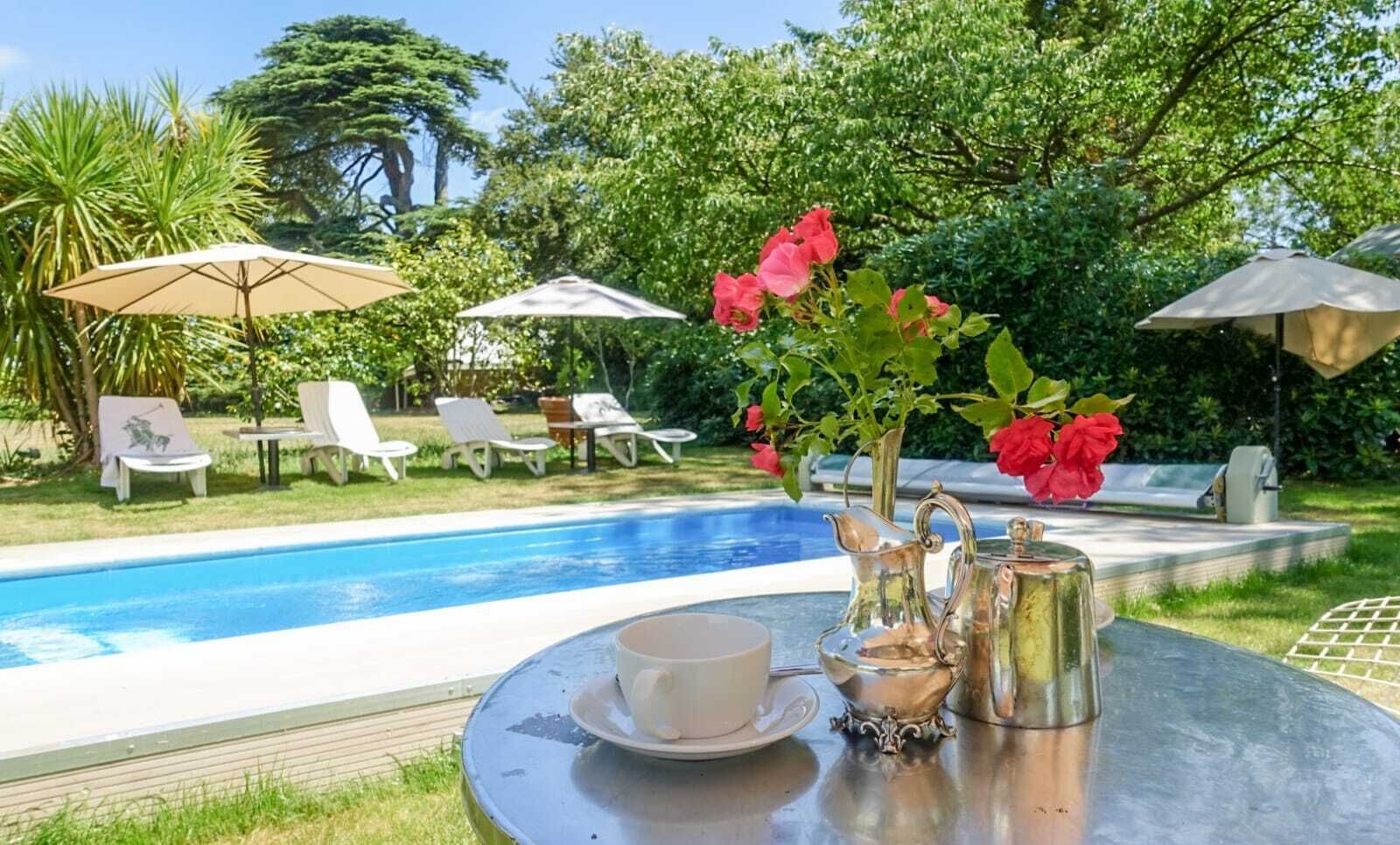 A poolside setting with a table, chairs, and umbrellas.