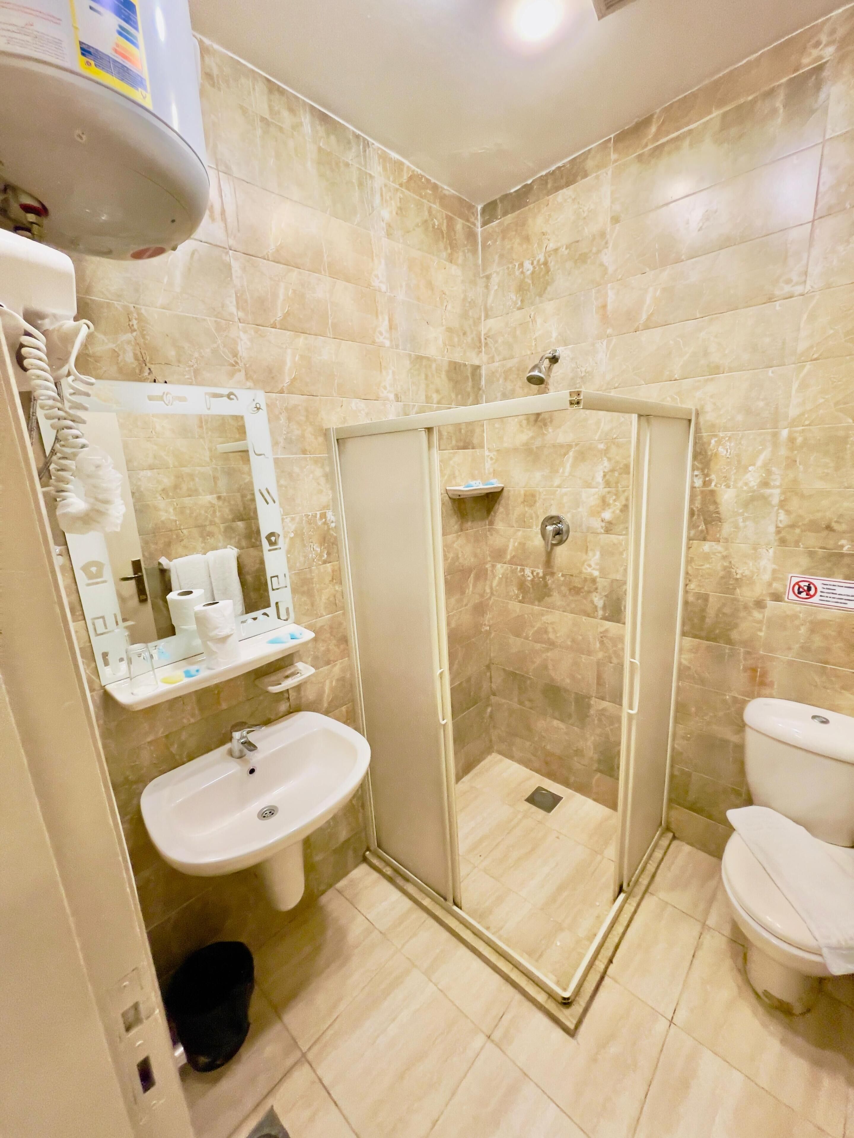 Une salle de bain équipée d’une douche, d’un lavabo, de toilettes et d’un miroir.