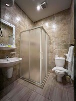 A bathroom with a glass-enclosed shower, a sink, a toilet, and a mirror.