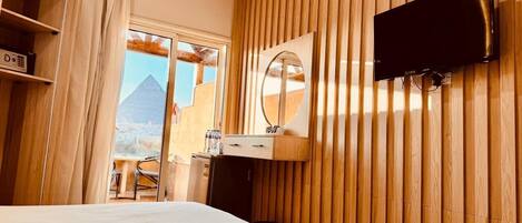 Een hotelkamer met een bed, een bureau met spiegel, een airconditioning en een televisie.
