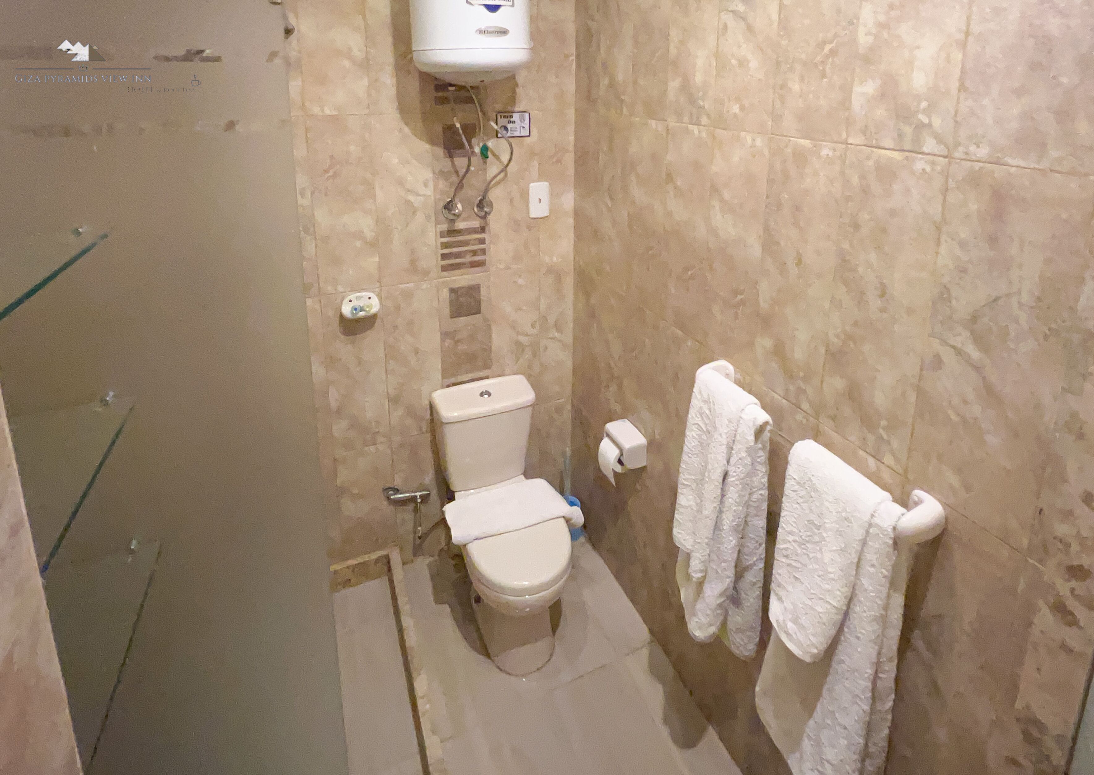 A bathroom with a toilet, a shower, and a towel rack.