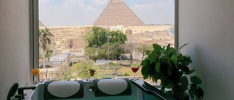 A bathroom with a bathtub, a window, and a view of the pyramid.