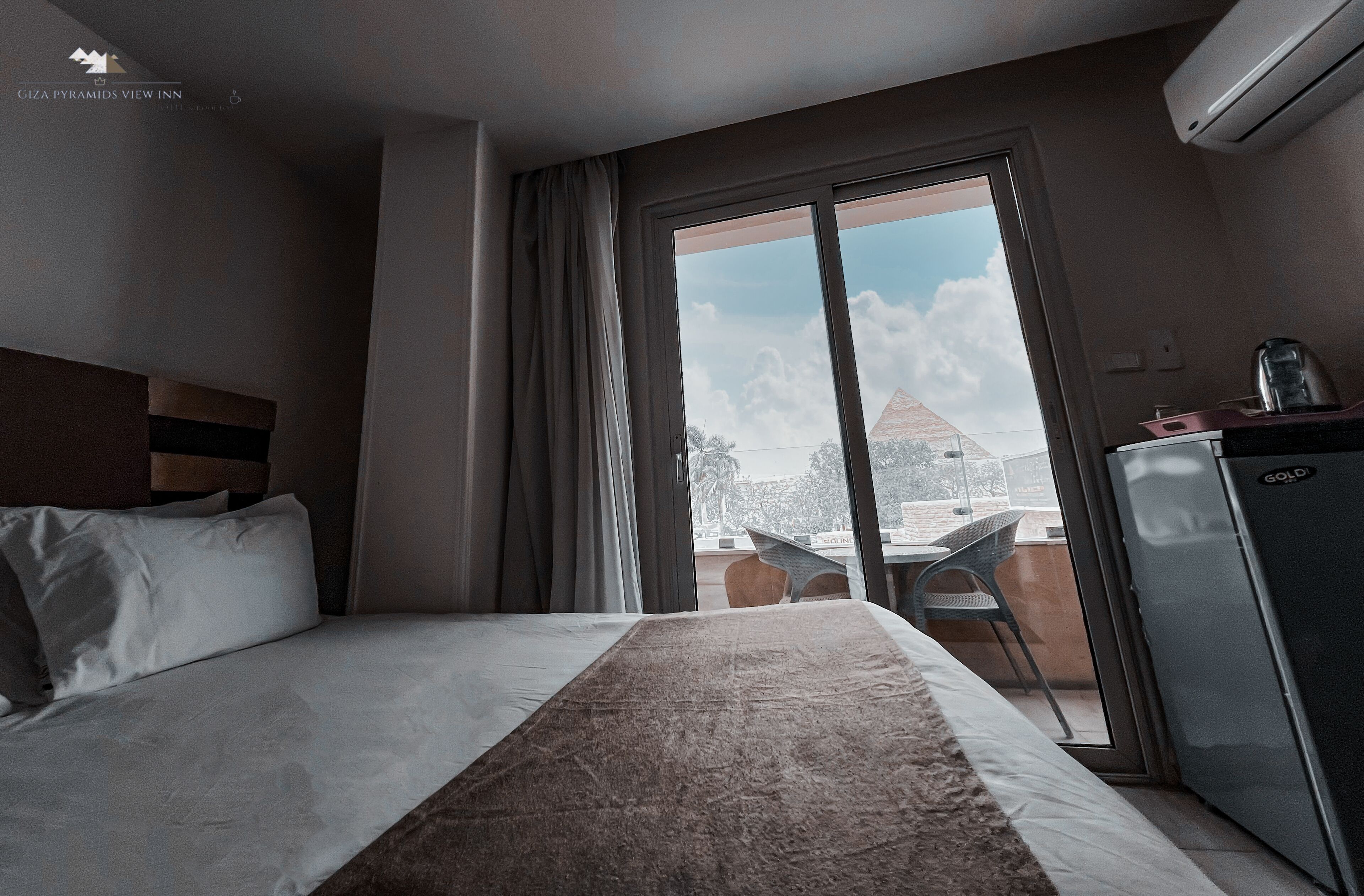 A hotel room with a bed, a desk, a chair, and a view of the outside.