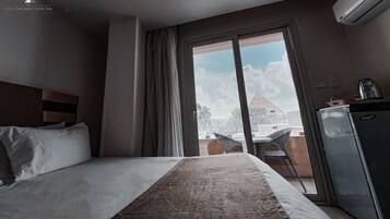 A hotel room with a bed, a desk, a chair, and a view of the outside.