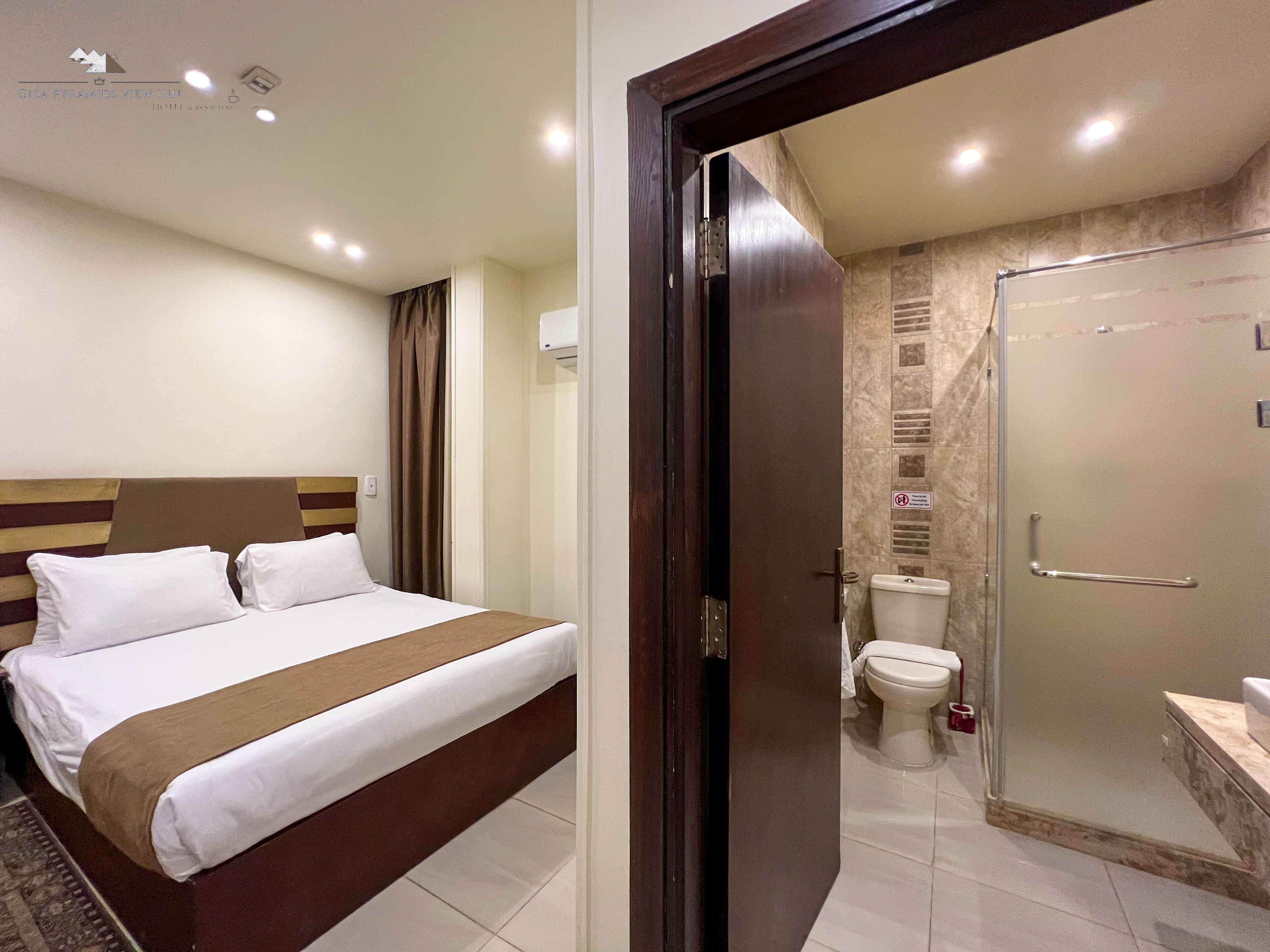 A hotel room with a bed, a shower, and a toilet.